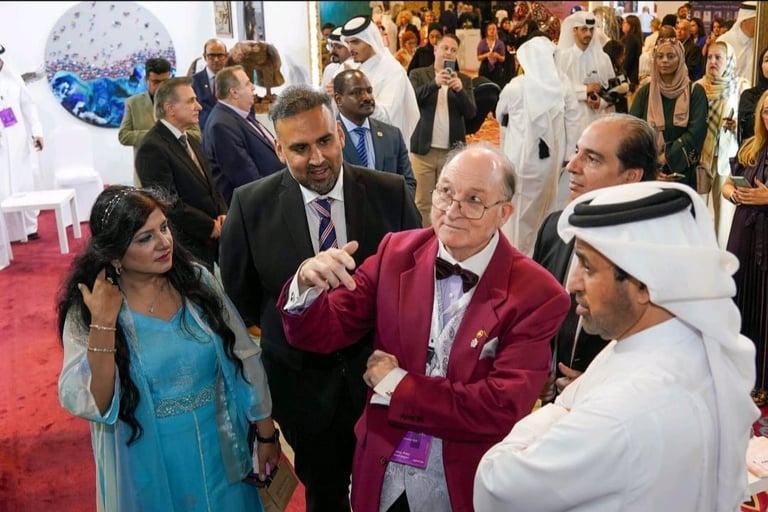 Man in burgundy blazer and glasses shaking hands with man in white headwear at crowded formal event on red carpet